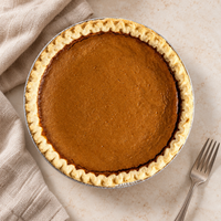 Brown’s Market Sweet Potato Pie in a foil pan on a neutral tabletop with linen and a dessert fork.