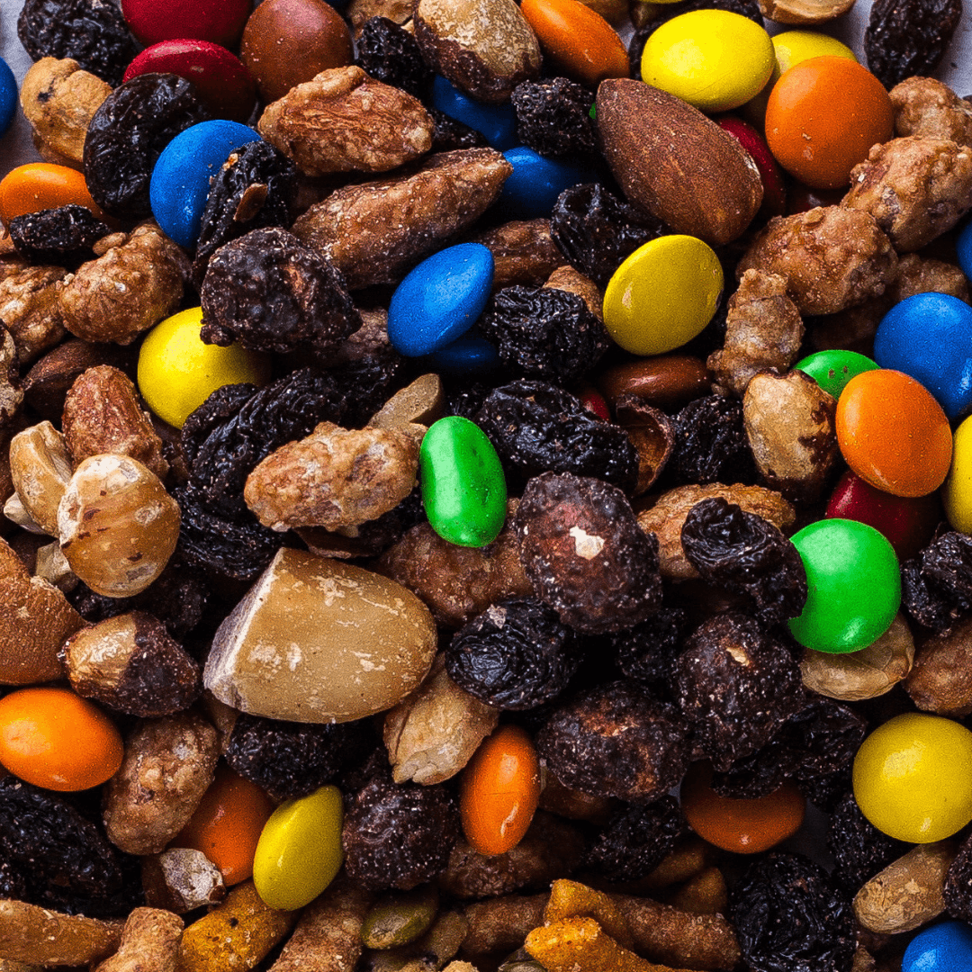 Close-up of a snack mix with nuts, raisins and colorful candy pieces