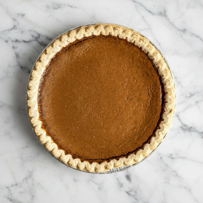 Whole sweet potato pie with a crimped crust in a foil pan, viewed from above