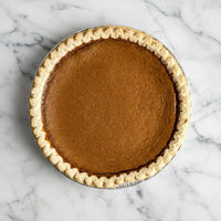 Whole sweet potato pie with a crimped crust in a foil pan, viewed from above