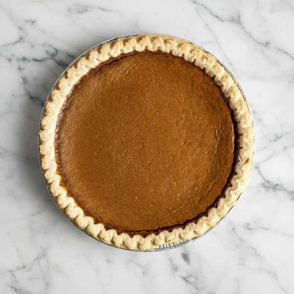 Whole sweet potato pie with a crimped crust in a foil pan, viewed from above