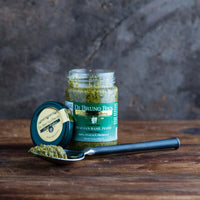 Open jar of Di Bruno Bros. basil pesto beside a spoonful of pesto