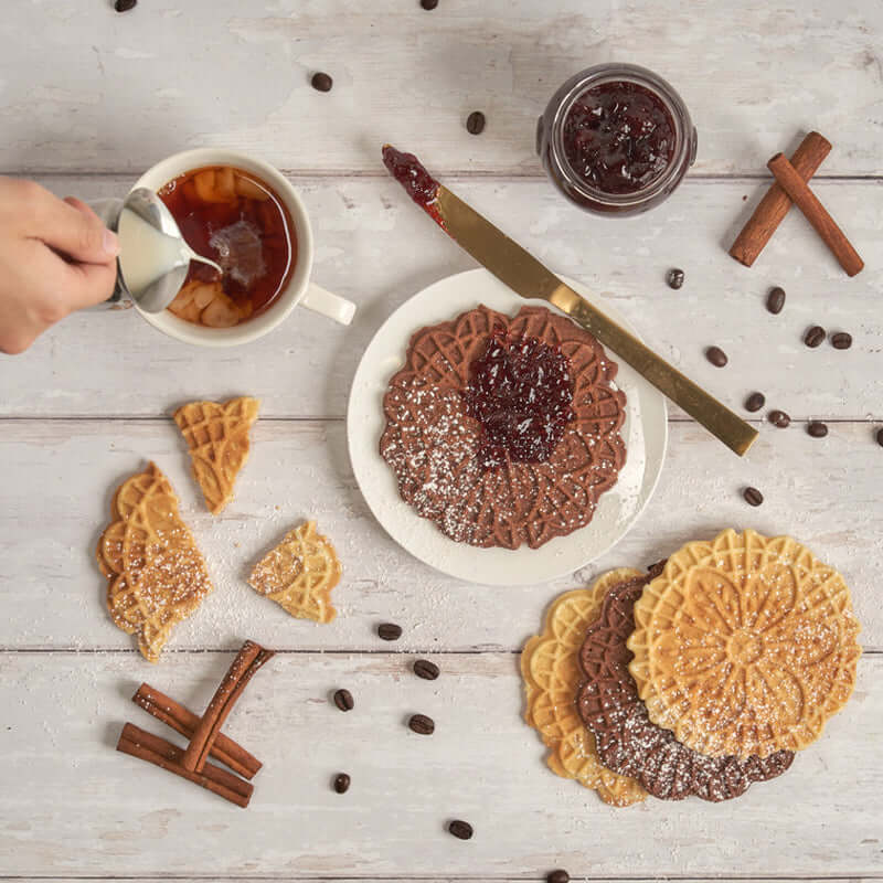 Assorted pizzelles served with tea and jam on a tabletop