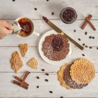 Assorted pizzelles served with tea and jam on a tabletop