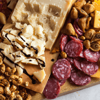 Close view of a styled charcuterie board with cheese, sliced cured meat, figs, and candied nuts