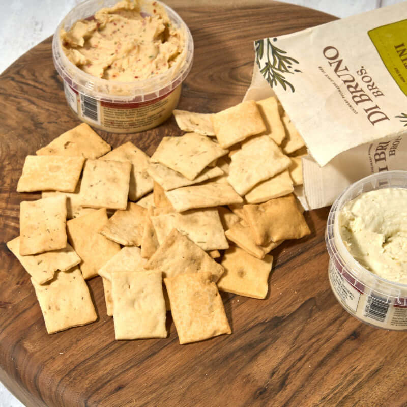 Di Bruno Bros. crostini crackers served on a wooden board with two cheese spreads