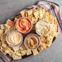 Four example cheese spreads in open tubs surrounded by Di Bruno Bros. crostini on a serving tray
