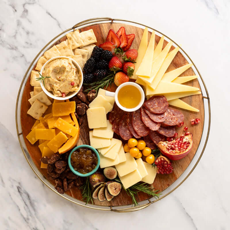 Overhead serving suggestion with cheeses, sliced salami, crostini, cheese spread, honey, jam, and candied nuts