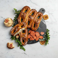 Pretzels on a serving board with dip and sliced sausage; photographed for a separate pretzel presentation