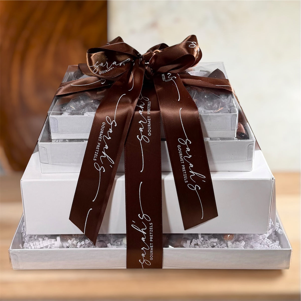 Front view of Sarah’s Gourmet Pretzels Gluten-Free Premium Gift Tower with stacked white boxes and brown branded ribbon