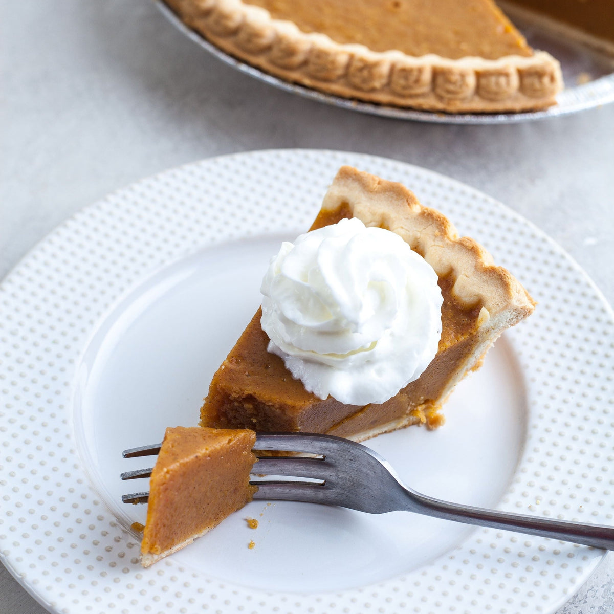 Slice of sweet potato pie topped with whipped cream on a plate